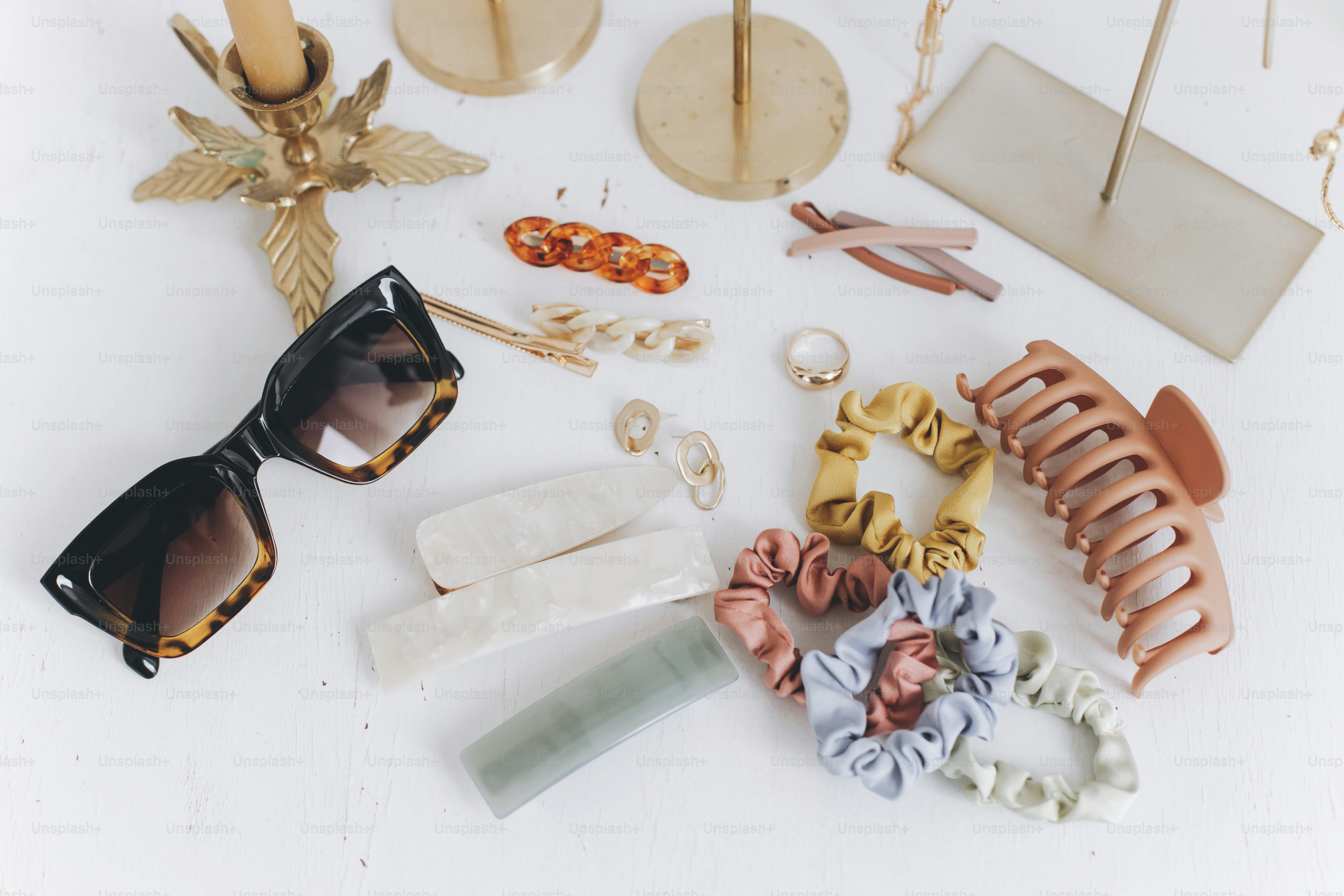 Tortoiseshell sunglasses, hair clips, and colorful fabric scrunchies on a white surface